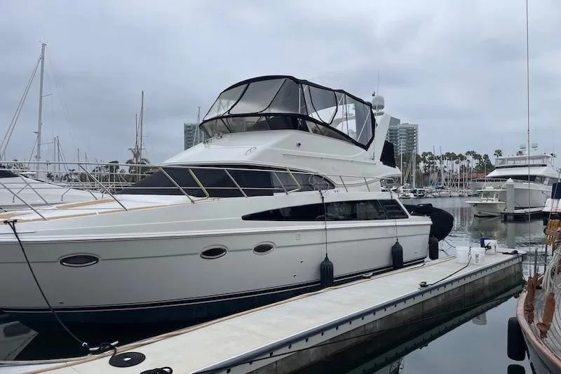 Slide: The Image of 2006 Carver 42 Super Sport yacht docked at a marina under cloudy skies. - 2