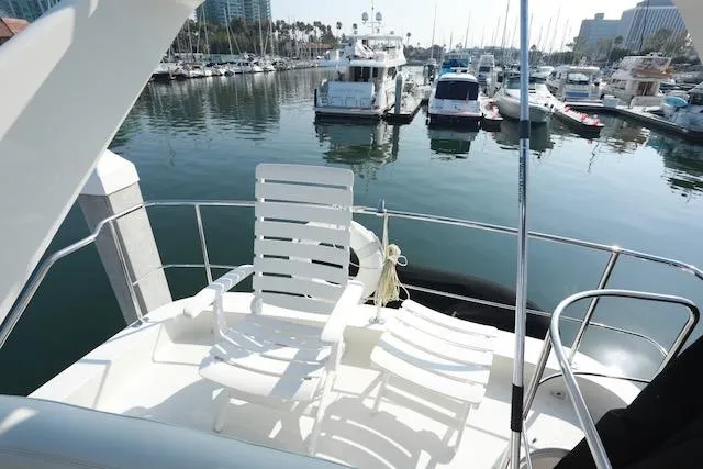 Slide: The Image of 2006 Carver 42 Super Sport yacht with deck chairs in a marina setting. - 25