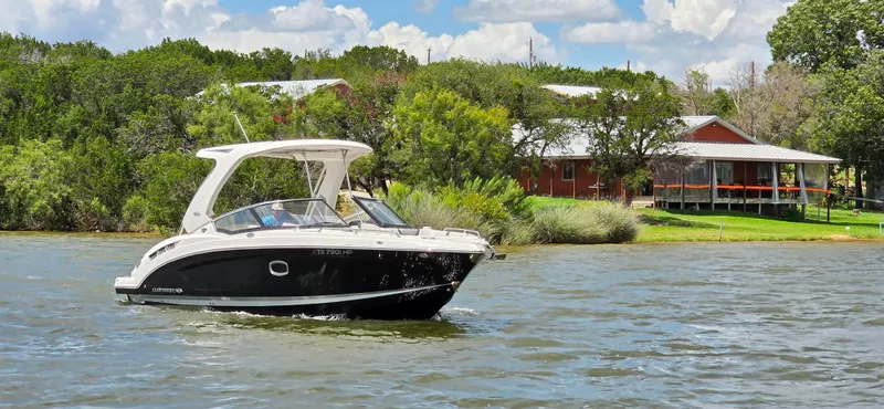 Slide: The Image of 2020 Chaparral 317 SSX boat cruising on a scenic lake near a lakeside house. - 12