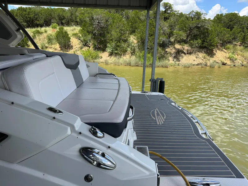 Slide: The Image of 2020 Chaparral 317 SSX boat with seating, docked by a scenic lakeside. - 31