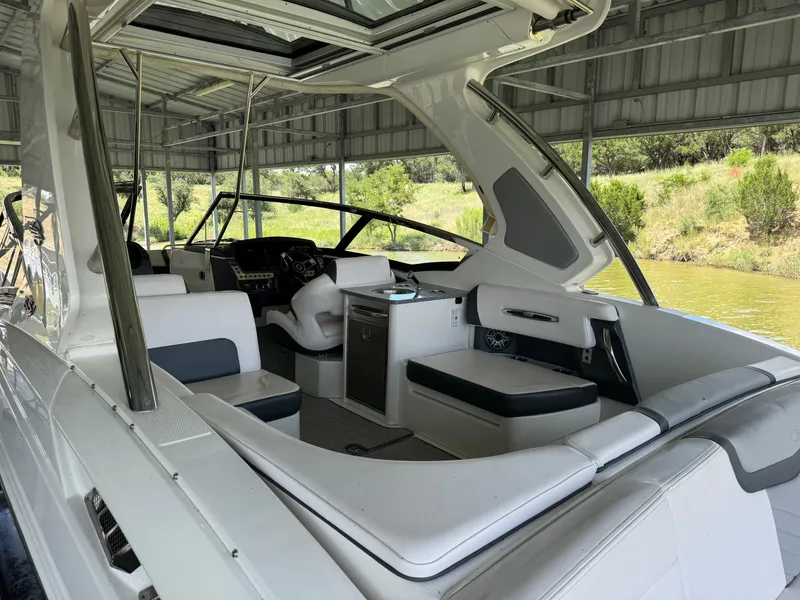 Slide: The Image of 2020 Chaparral 317 SSX boat interior with seating and helm under a covered dock. - 32