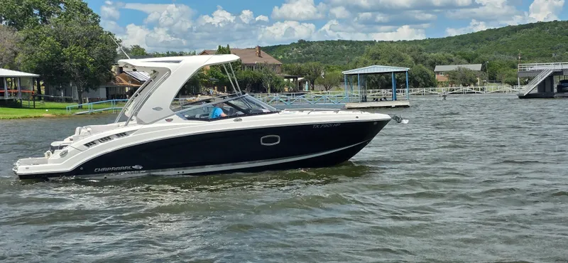 Slide: The Image of 2020 Chaparral 317 SSX boat cruising on a scenic lake with lush green hills. - 9