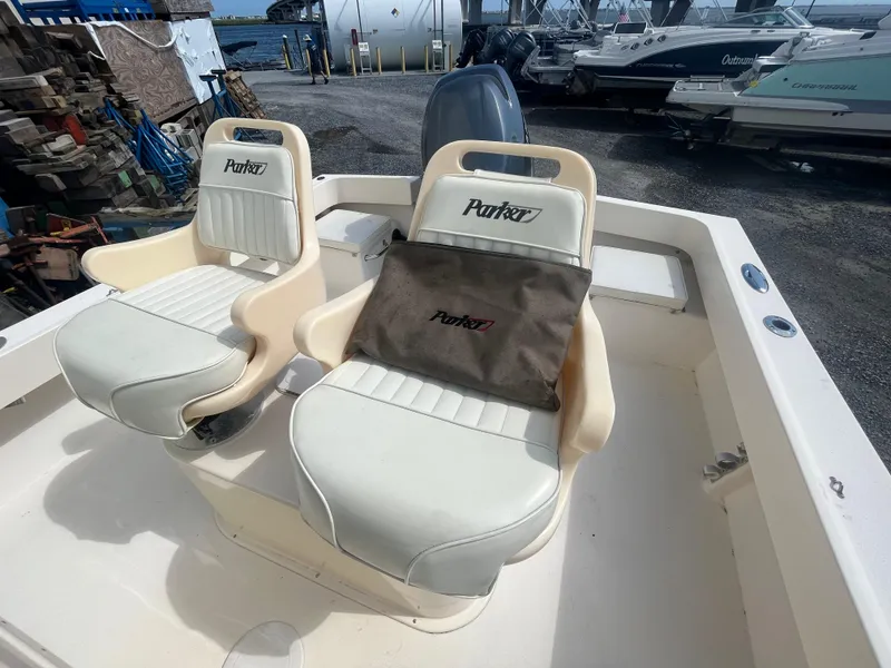 Slide: The Image of 2011 Parker 21SE Center Console boat seats, white with Parker logo, docked near other boats. - 18