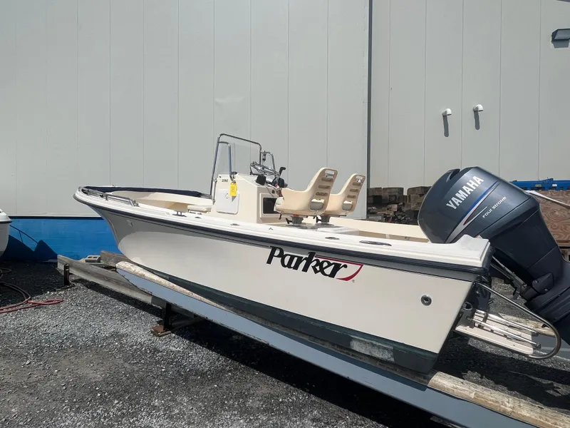 Slide: The Image of 2011 Parker 21SE Center Console boat with Yamaha outboard engine, parked on gravel. - 2