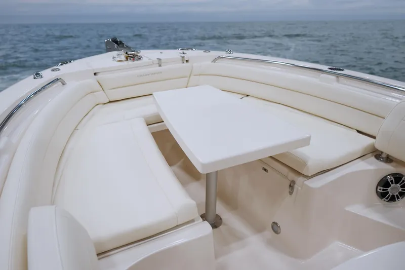 Slide: The Image of 2025 Grady-White Fisherman 236 boat interior with cushioned seating and table, ocean backdrop. - 9