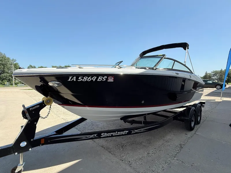Slide: The Image of 2018 Monterey 218 Super Sport boat on trailer, parked outdoors under clear blue sky. - 2