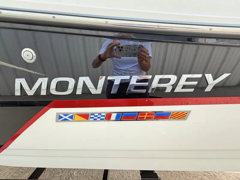 Slide: The Image of 2018 Monterey 218 Super Sport boat with nautical flags and reflective surface. - 5