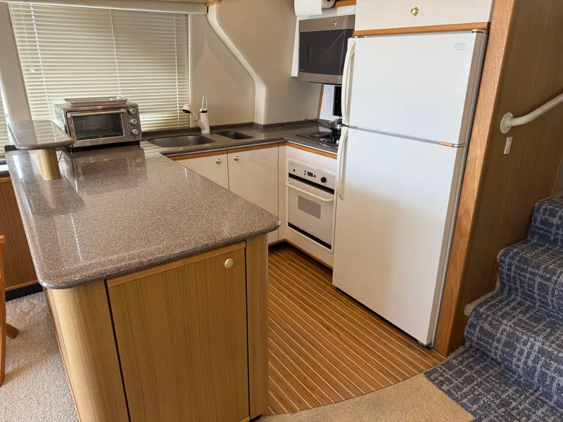 Slide: The Image of 2001 Bayliner 5288 Pilot House Motoryacht kitchen with modern appliances and wood accents. - 23