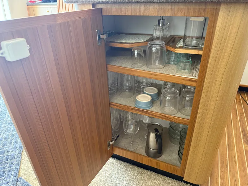 Slide: The Image of Open cabinet on 2001 Bayliner 5288 yacht, displaying neatly arranged glassware and kitchen items. - 25
