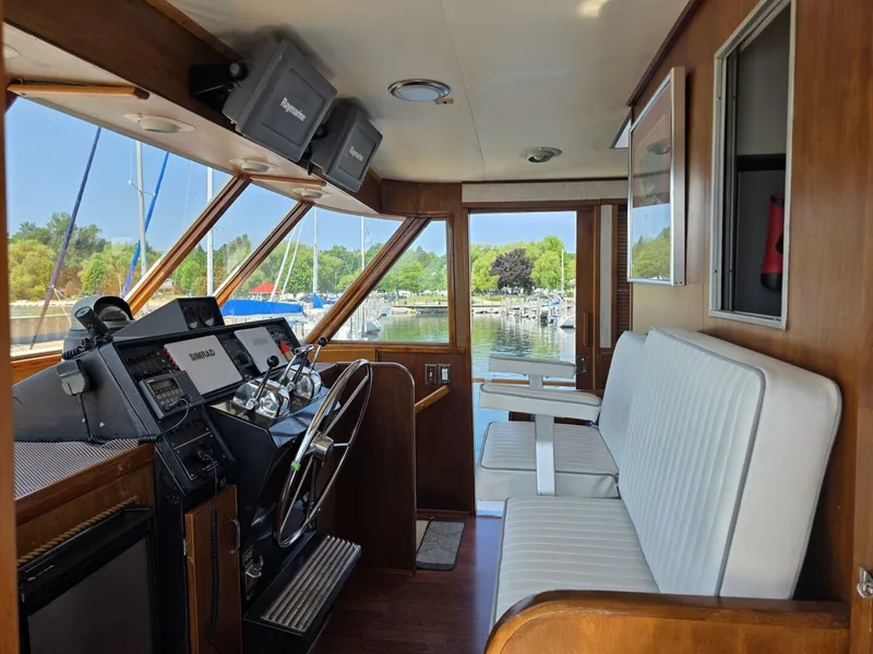 Slide: The Image of 1976 Chris-Craft Roamer 60 yacht interior with helm, white seating, and marina view. - 11