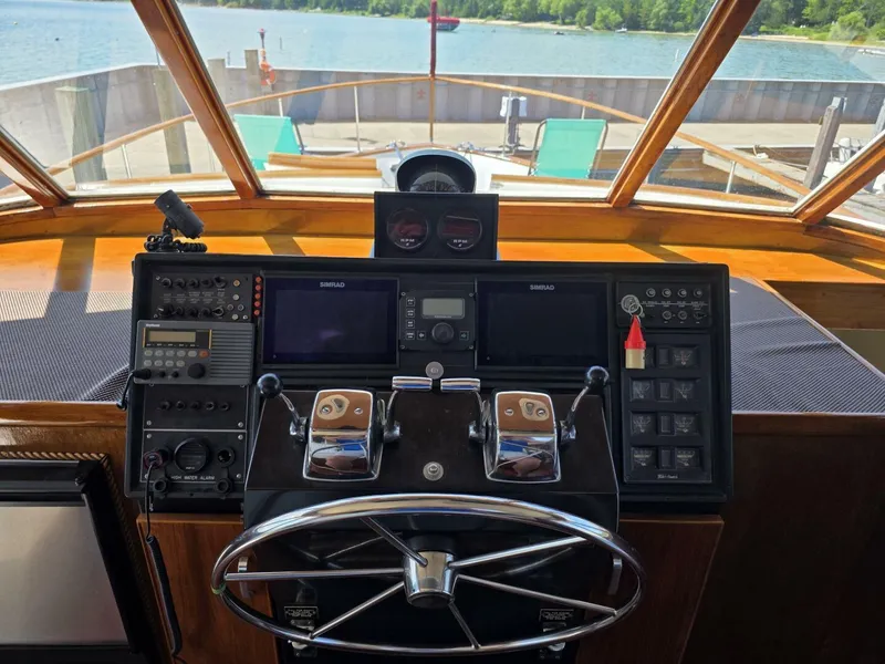 Slide: The Image of Helm of 1976 Chris-Craft Roamer 60 yacht with modern navigation equipment, overlooking serene waters. - 12