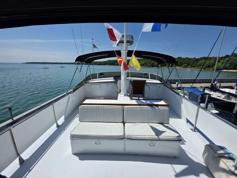Slide: The Image of 1976 Chris-Craft Roamer 60 yacht deck with seating, flags, and scenic water view. - 22