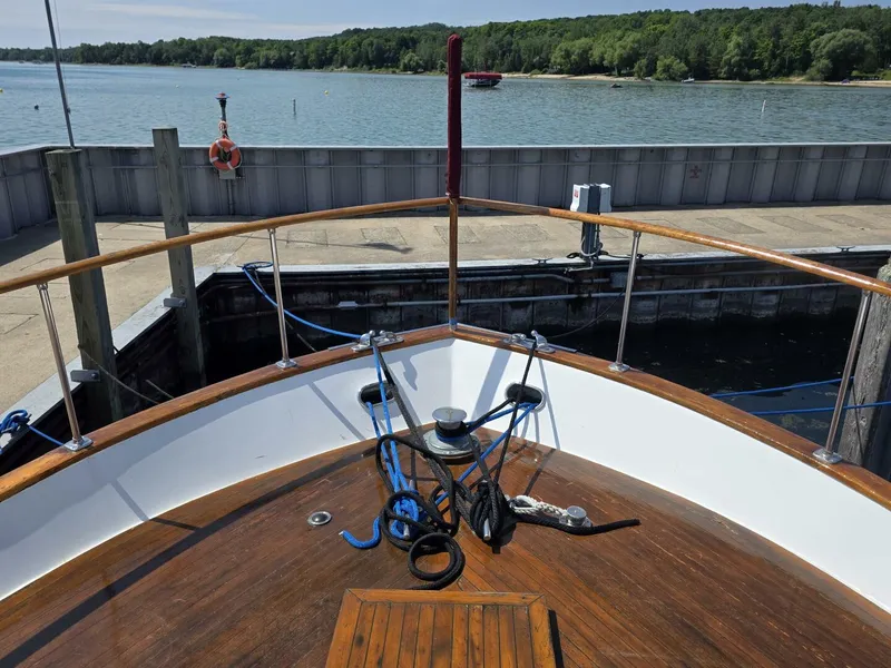 Slide: The Image of 1976 Chris-Craft Roamer 60 yacht docked by a serene lake with lush greenery. - 6