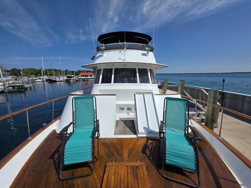 Slide: The Image of 1976 Chris-Craft Roamer 60 yacht with deck chairs, docked at a marina under a clear blue sky. - 8