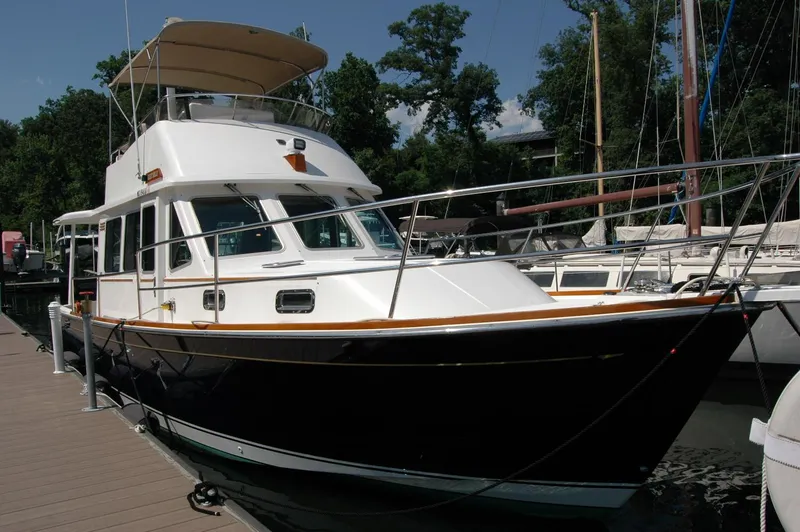 Slide: The Image of 2006 Sabre 36 Flybridge Sedan docked at marina, surrounded by trees and other boats. - 1