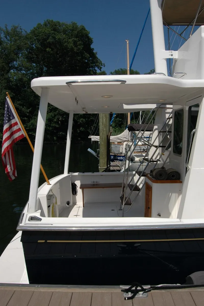 Slide: The Image of 2006 Sabre 36 Flybridge Sedan docked, featuring spacious deck and American flag. - 10