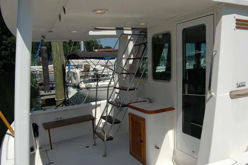 Slide: The Image of 2006 Sabre 36 Flybridge Sedan yacht with ladder, bench, and docked boats in background. - 22