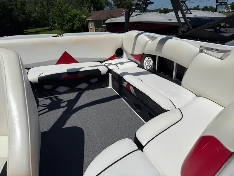 Slide: The Image of 2011 Axis A22 boat interior with white and red seating, outdoor setting. - 17