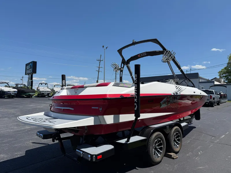 Slide: The Image of 2011 Axis A22 boat on trailer at dealership under clear blue sky. - 4