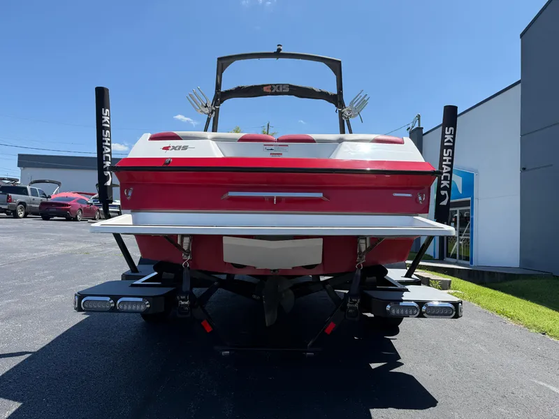 Slide: The Image of 2011 Axis A22 boat, red and white, parked outdoors on a sunny day. - 5