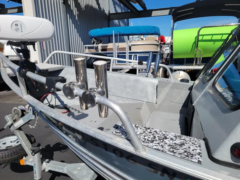 Slide: The Image of 2018 Klamath 18 OPW boat with rod holders and motor, parked in a marina. - 10