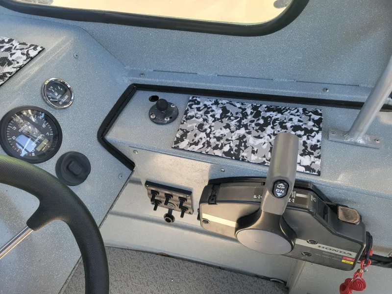Slide: The Image of 2018 Klamath 18 OPW boat dashboard with steering wheel, controls, and gauges. - 15