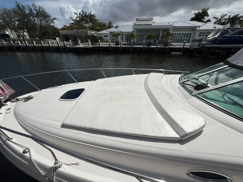 Slide: The Image of 2005 Sea Ray 340 Sundancer yacht docked by waterfront homes under cloudy skies. - 2