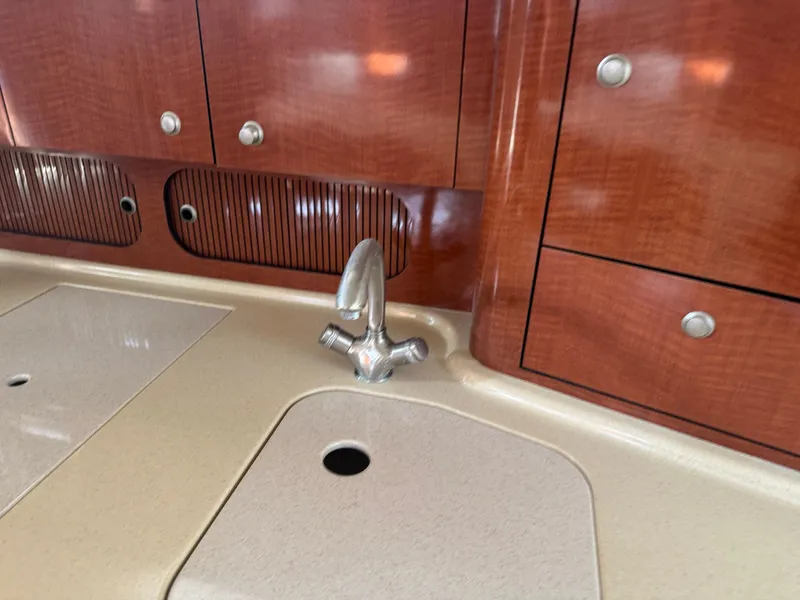 Slide: The Image of 2005 Sea Ray 340 Sundancer kitchen sink with wooden cabinetry and chrome faucet. - 25