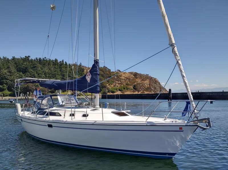 The Image of Catalina 36 MkII sailboat from 2002 on calm water near a forested shoreline. - 0