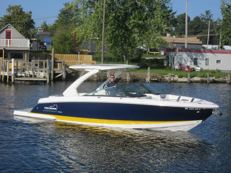Slide: The Image of 2021 Chaparral 307 SSX boat cruising on a calm river near a dock. - 4