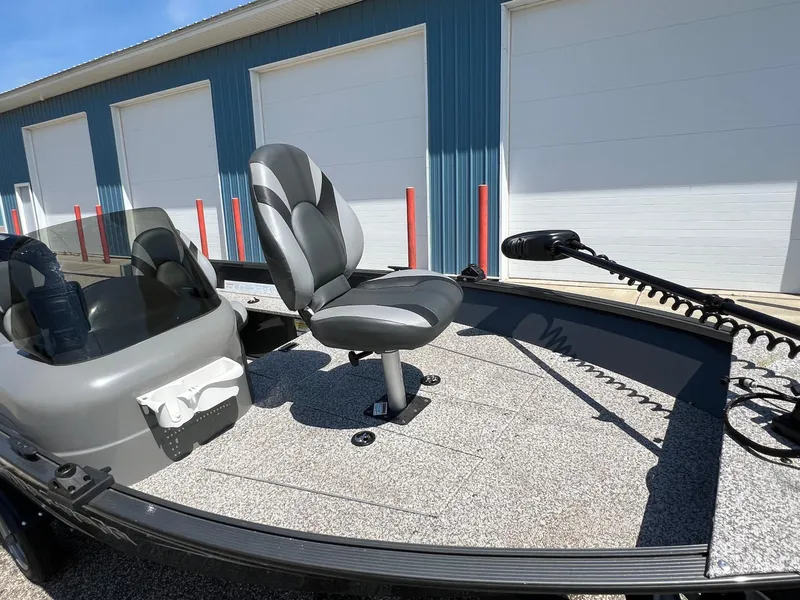 Slide: The Image of 2021 MirroCraft 145 Side Console boat with seating and trolling motor, parked near blue building. - 15