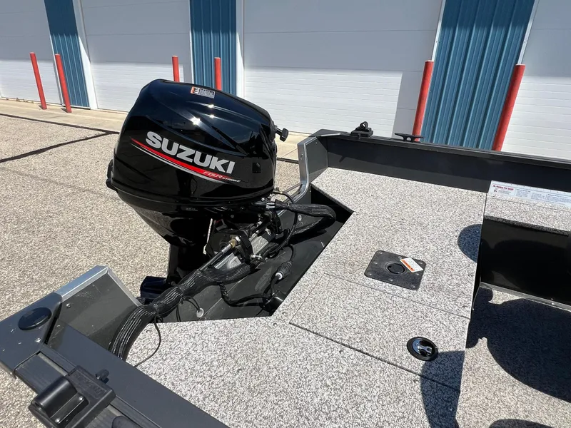 Slide: The Image of 2021 MirroCraft 145 Side Console boat with Suzuki outboard motor in a parking area. - 18