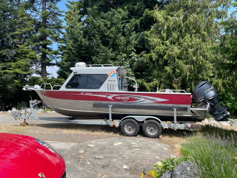 The Image of 2019 Hewescraft 240 Ocean Pro boat on trailer, surrounded by lush greenery. - 0