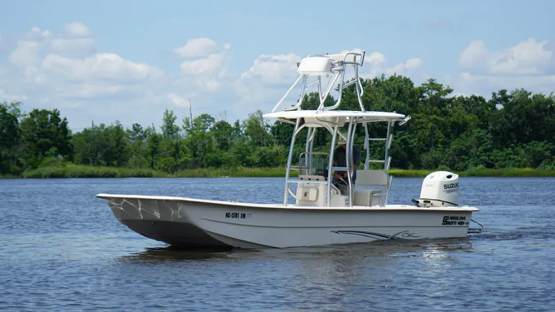 Slide: The Image of 2019 Carolina Skiff 24 DLX boat on a calm lake with lush green background. - 4