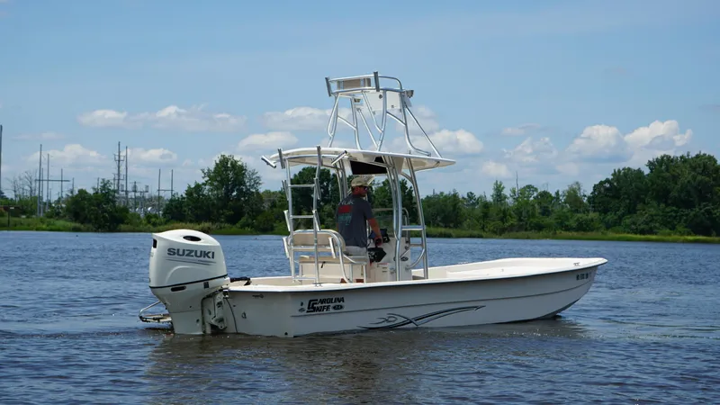 Slide: The Image of 2019 Carolina Skiff 24 DLX boat with Suzuki engine on a calm river. - 5