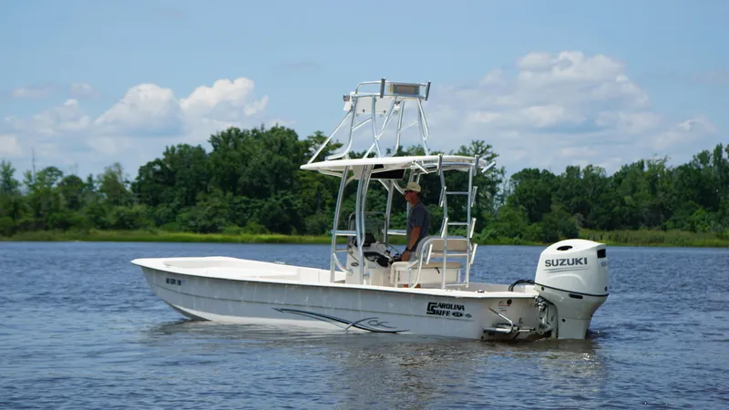 Slide: The Image of 2019 Carolina Skiff 24 DLX boat on a calm lake with trees in the background. - 7