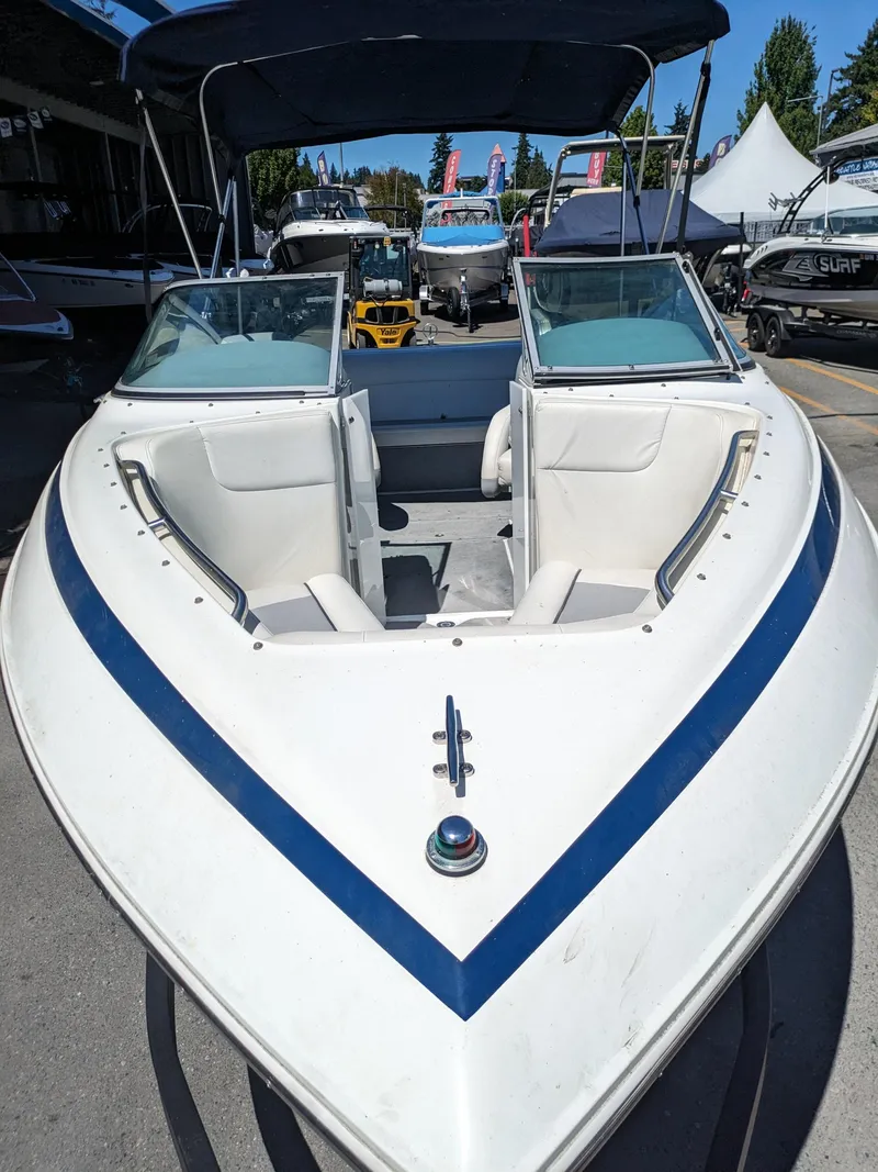 Slide: The Image of 1998 Cobalt 200 boat with blue stripe, open bow seating, and canopy in a marina setting. - 7