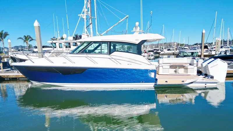 Slide: The Image of 2025 Tiara Yachts 43 LE in marina, sleek design, blue and white exterior. - 2