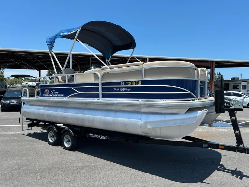 The Image of 2018 Sun Tracker Party Barge 20 DLX pontoon boat on trailer, parked outdoors. - 0