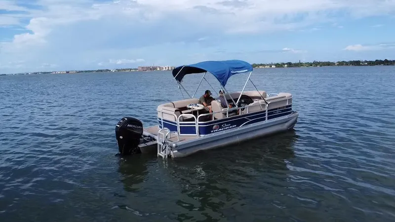 Slide: The Image of 2018 Sun Tracker Party Barge 20 DLX pontoon boat on calm water with blue canopy. - 13