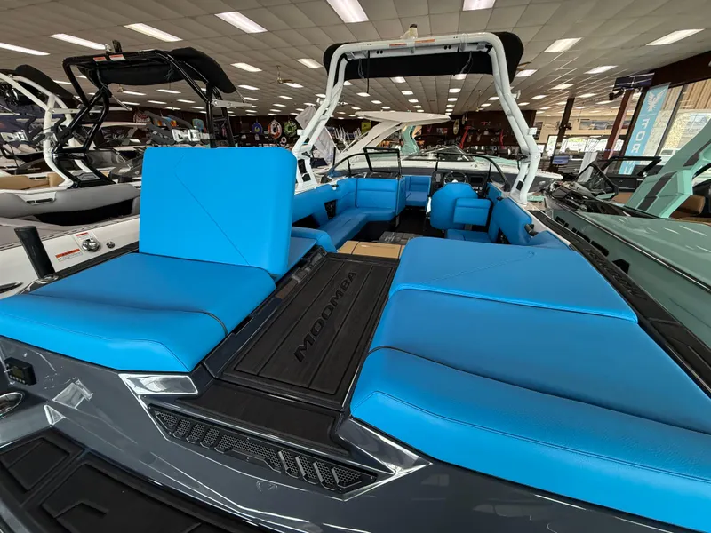 Slide: The Image of 2025 Moomba Tykon boat with vibrant blue seating in a showroom. - 10