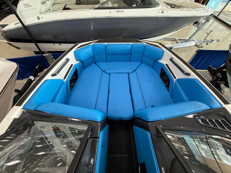 Slide: The Image of 2025 Moomba Tykon boat interior with vibrant blue seating, showcased in a showroom. - 23