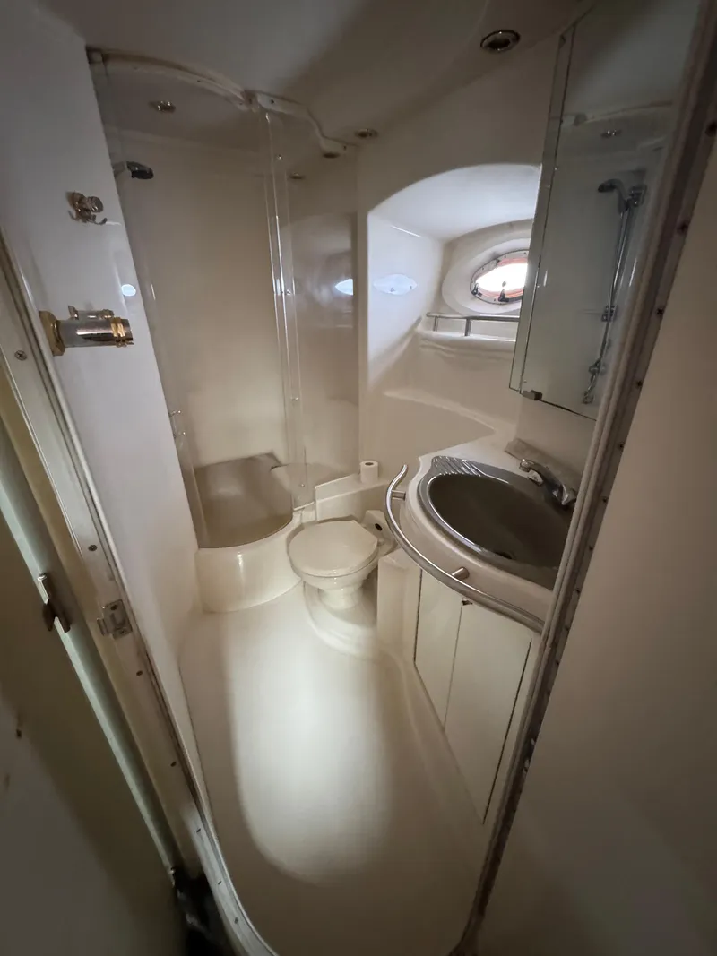Slide: The Image of Compact bathroom in a 1998 Maxum 4600 SCB yacht, featuring shower, toilet, and sink. - 28