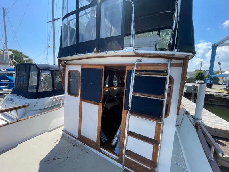 Slide: The Image of 1982 Californian 34 LRC boat docked, featuring a wooden ladder and enclosed upper deck. - 13