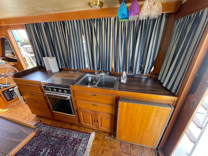 Slide: The Image of 1982 Californian 34 LRC yacht kitchen with wood cabinetry, stove, sink, and striped curtains. - 26