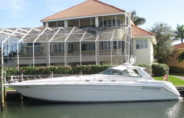 The Image of 1994 Sea Ray 500 Sundancer yacht docked by a waterfront house with a screened patio. - 0