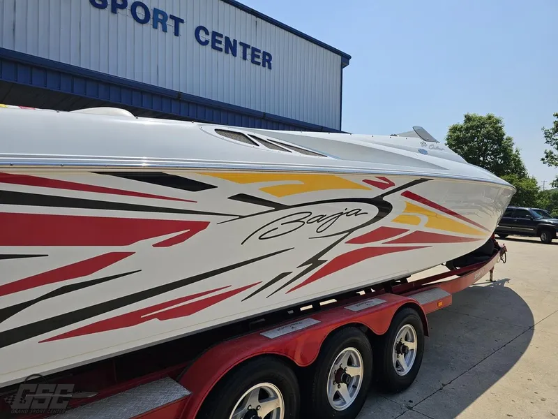 Slide: The Image of 2005 Baja 33 Outlaw boat with vibrant graphics on a trailer at a sport center. - 12