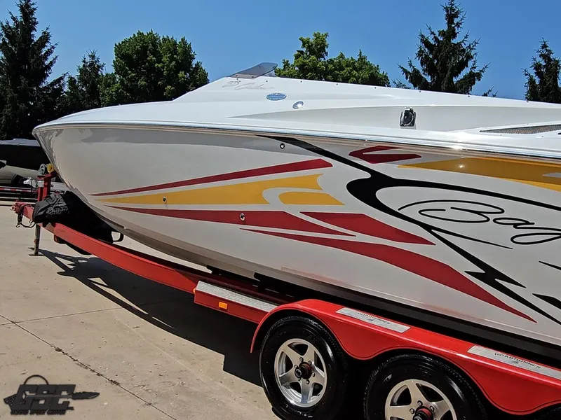 Slide: The Image of 2005 Baja 33 Outlaw boat on red trailer, vibrant graphics, sunny day. - 26