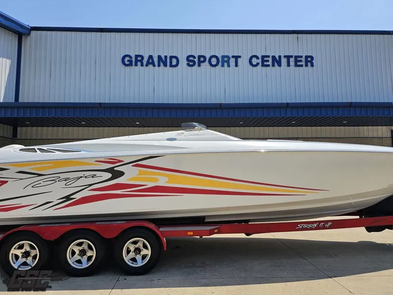Slide: The Image of 2005 Baja 33 Outlaw boat at Grand Sport Center, featuring vibrant graphics and a red trailer. - 3