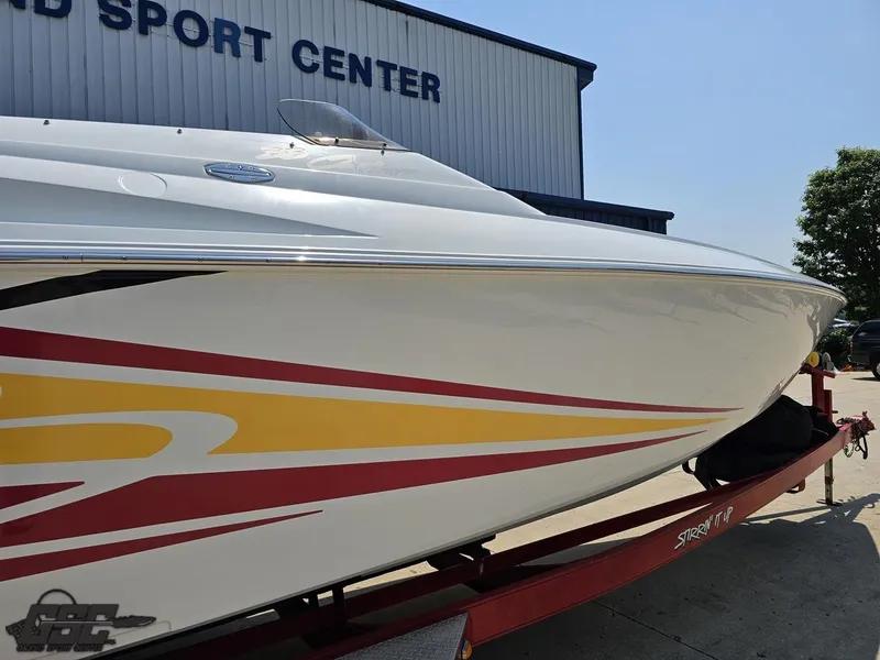 Slide: The Image of 2005 Baja 33 Outlaw boat with colorful graphics on a trailer outside a sport center. - 8